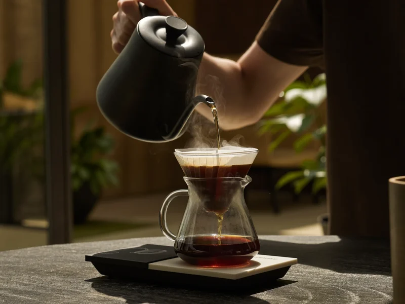 Caffè filtro versato a mano che gocciola in una caraffa di vetro